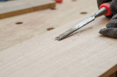 Woodworker using chisel cuts slot on wooden board close up