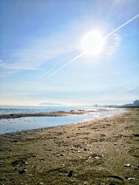 Scenic view of beach against blue sky on sunny day