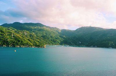 Scenic view of sea by mountains against sky