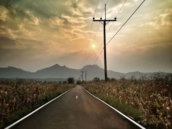 Road by mountain against sky during sunset