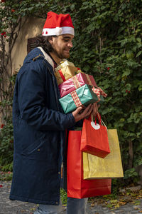 The young man in the santa hat brings the newly purchased gifts and hopes not to drop them.