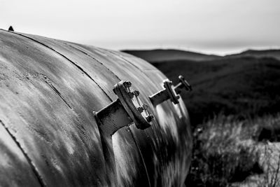 Close-up of rusty metallic container on field