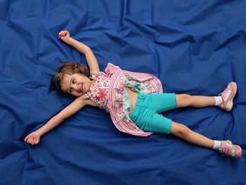 High angle view of girl lying on blue sheet