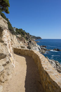 Rock formation on beach against clear blue sky