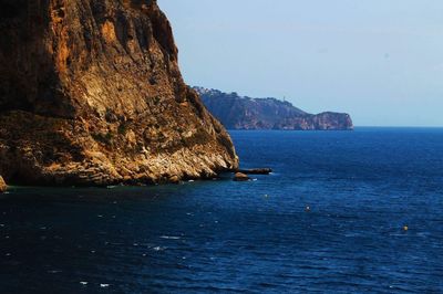 Scenic view of sea and rock formations against clear sky