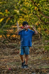 Full length portrait of happy boy standing on tree