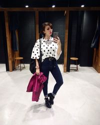 Stylish woman holding smart phone while standing in restroom