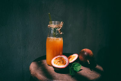 Close-up of drink and passion fruits on table in darkroom