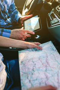 Young couple reading map on digital tablet in car