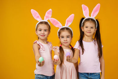 Portrait of happy friends standing against yellow background