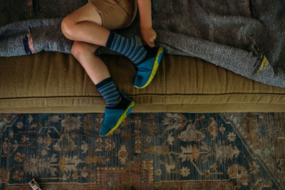 Young boy sitting on couch putting on shoes