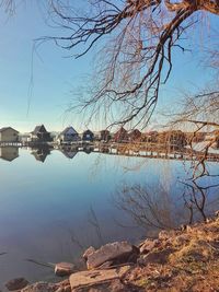 Reflection of bare trees in lake against sky