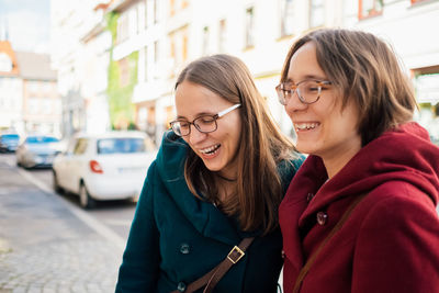 Laughing friends standing on street in city