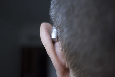 Close-up of human ear with hearing aid against black background