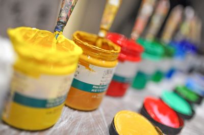 Close-up of multi colored paint in containers on table