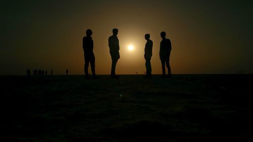 Silhouette people on field against sky during sunset