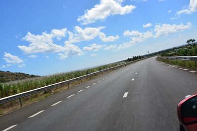 Road leading towards highway against sky