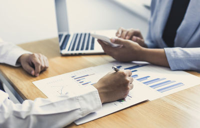 Midsection of businessman and colleague working at table