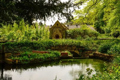 Built structure by lake against trees and plants