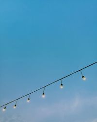 Low angle view of lighting equipment against clear blue sky