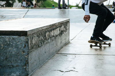 Low section of man skateboarding on footpath