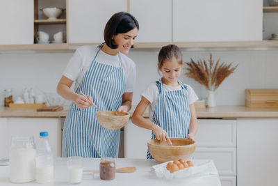 Mother and daughter standing in kitchen at home