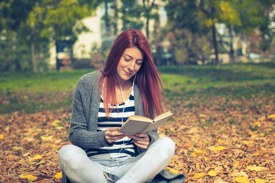 Full length of woman sitting on book in autumn