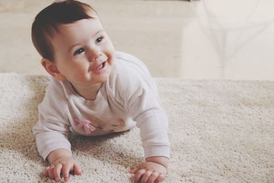 Smiling girl crawling on carpet at home