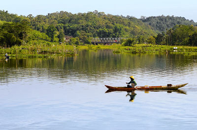 Natural landscape green hill background lake foreground a fisherman with his canoe