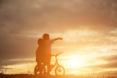 Silhouette man riding motorcycle against sky during sunset