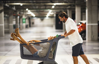 Man carrying wife in shopping cart