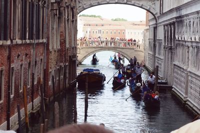 People in traditional gondolas amidst buildings