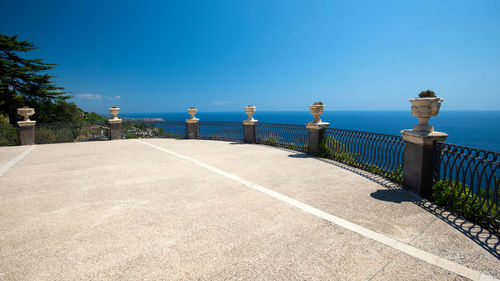 Rear view of man walking on road against clear blue sky