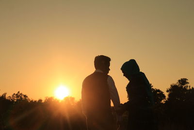 Silhouette man standing against orange sky during sunset