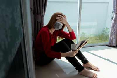 Woman sitting by window at home