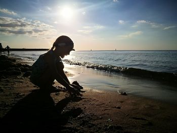 Silhouette woman standing on beach against sky during sunset