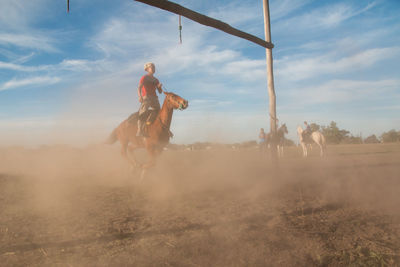 Man riding horse on landscape against sky