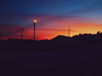 Silhouette electricity pylon against sky at sunset