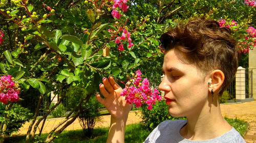 Portrait of beautiful woman by pink flowers at park