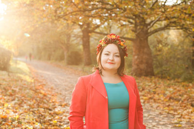 Portrait of smiling young woman standing against trees during autumn