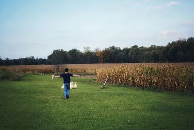 Rear view of man standing on field against sky