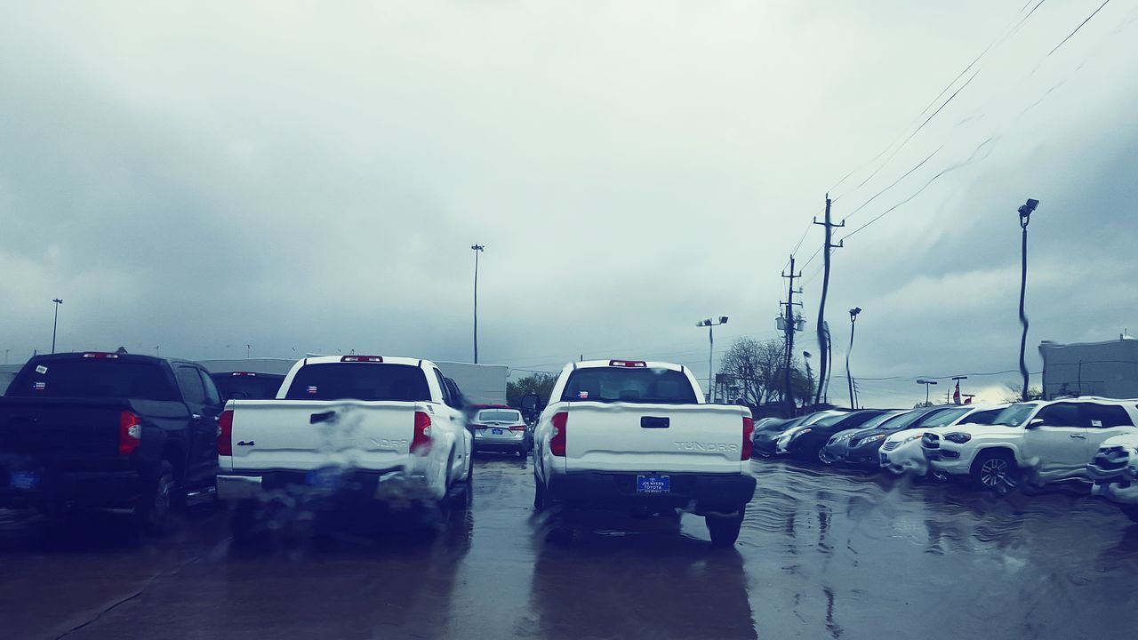 transportation, car, mode of transport, land vehicle, street, road, wet, sky, weather, rain, street light, water, cloud - sky, building exterior, overcast, built structure, season, road marking, city, architecture