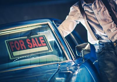 Midsection of man standing by car