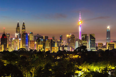 Illuminated buildings in city against sky at night