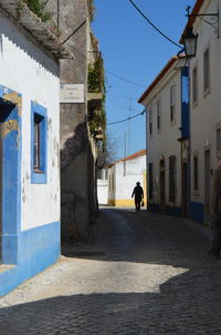 Person walking on pathway amidst buildings on sunny day