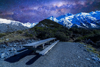 Empty bench on snowcapped mountain against sky