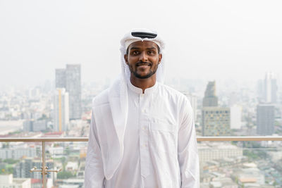 Portrait of young man standing against buildings