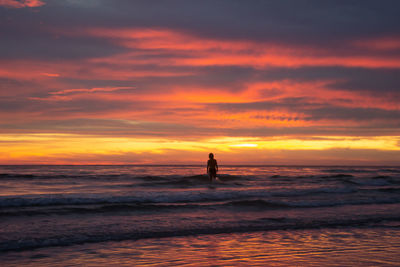 Silhouette person on beach against sky during sunset