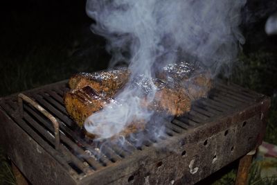 Close-up of meat steaks on barbeque at night
