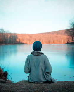 Rear view of person relaxing by lake